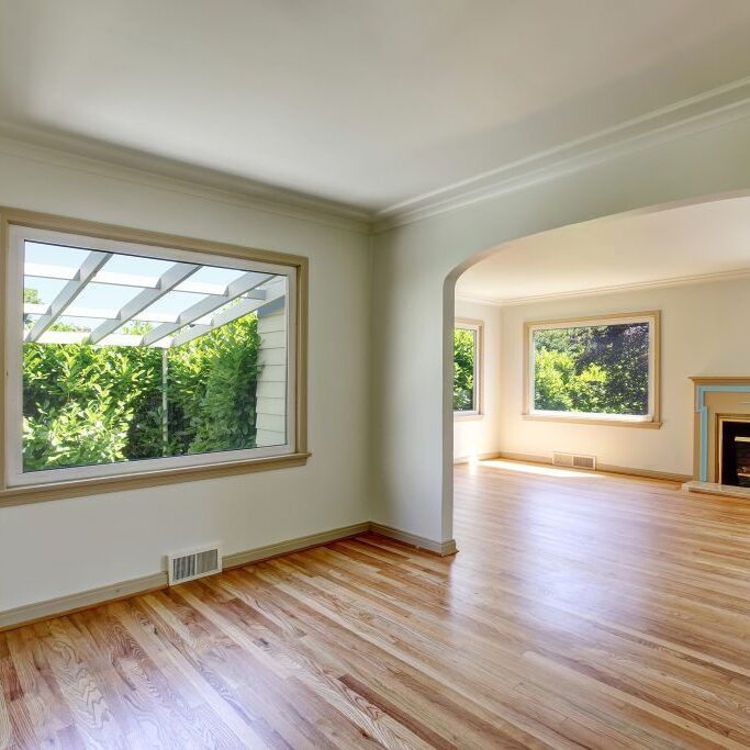 Open floor plan empty living room interior with polished hardwood floor and fireplace. Northwest USA